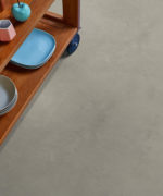 Фрагмент укладки плитки Tarkett iD Tilt Polished Concrete Steel у деревянной стеллажной стойки.