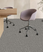 Пример укладки темно-серой ковровой плитки Desso Evolve в интерьере современного офиса с рабочими столами и стильными офисными креслами.