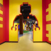 Желтый линолеум Tarkett в интерьере игровой зоны LEGO с оригинальным проходом в стене в форме силуэта фигурки человечка.