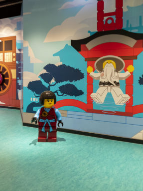 Бирюзовый линолеум Tarkett в интерьере игровой зоны LEGO Ninjago с фигуркой ниндзя на фоне стены в восточном стиле.