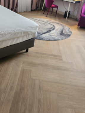 Виниловая плитка Tarkett iD Inspiration с укладкой елочкой и круглый ковер в интерьере номера отеля Mercure Riga Centre Hotel