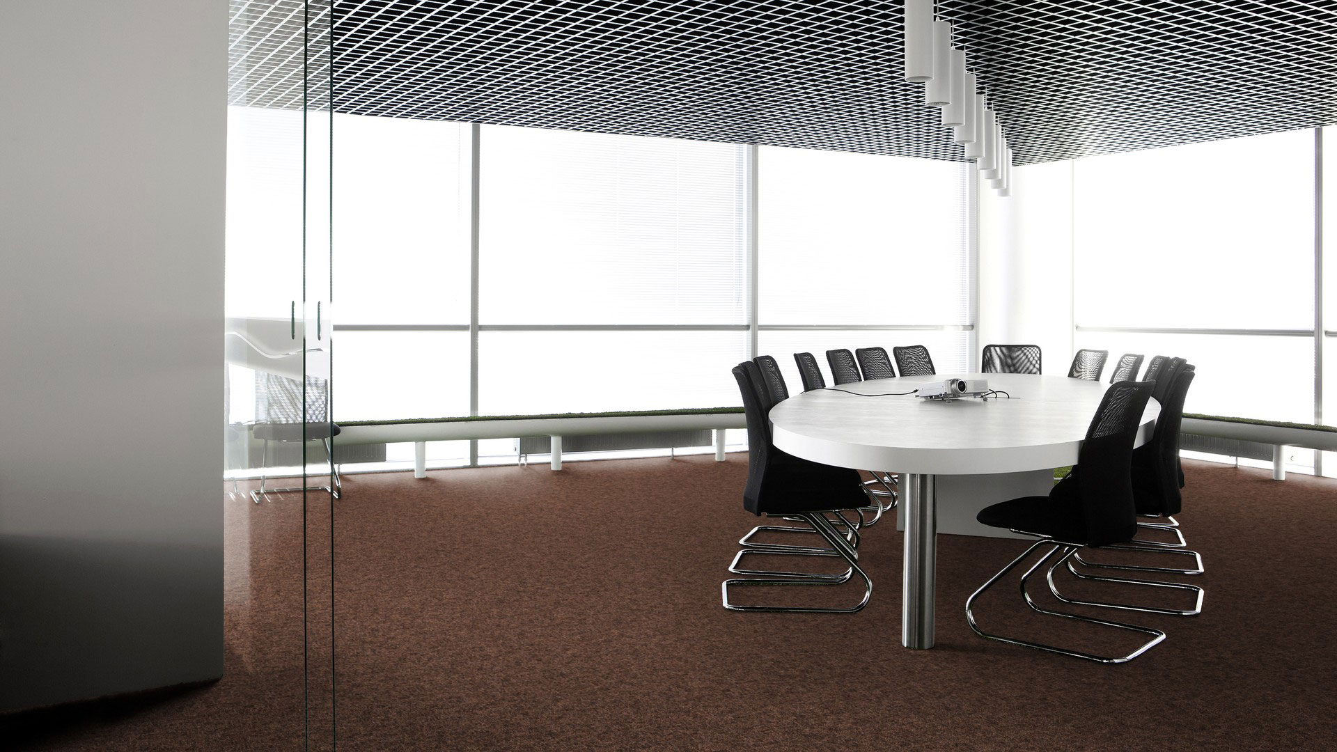Ковровая плитка Desso Metallic Shades 2083 в интерьере переговорной комнаты с большим белым столом, черными стульями и потолком грильято.