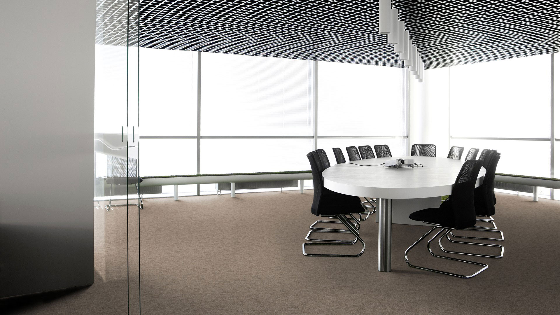 Ковровая плитка Desso Metallic Shades 2913 в интерьере переговорной с овальным столом, черными стульями и панорамным видом через стеклянную дверь.