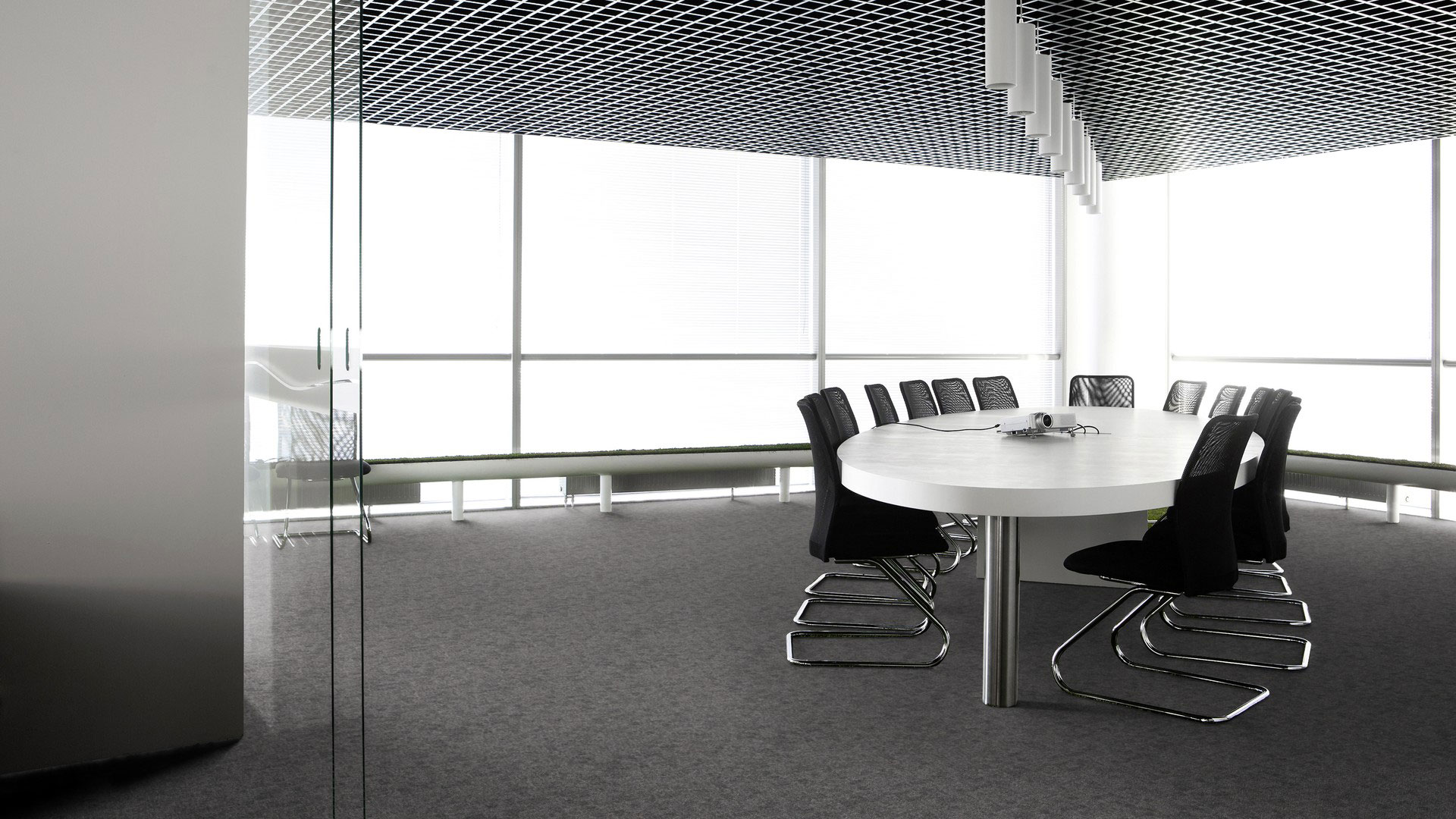 Ковровая плитка Desso Metallic Shades 9950 серого цвета в интерьере современной офисной переговорной комнаты с круглым столом.