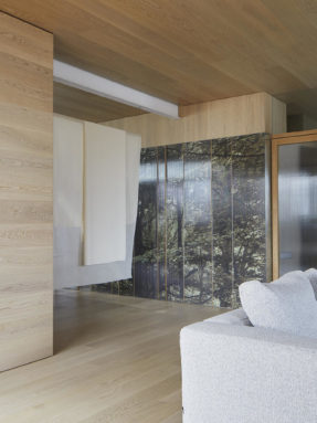 Паркетная доска Tarkett Shade Oak Cream White на полу и потолке подчеркивает геометрию минималистичной гостиной с лаконичным серым диваном.