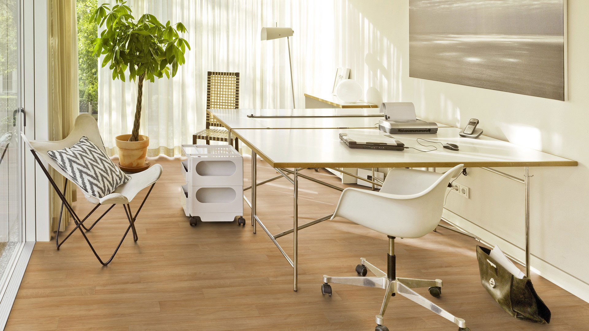 Линолеум Tarkett Heritage Topaz Antik Oak Light Brown светло-коричневого цвета в интерьере светлого домашнего офиса с рабочими столами и креслом