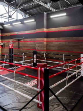 Черное спортивное покрытие Tarkett Omnisports в интерьере зала World Class с боксерским рингом и подвесным боксерским мешком