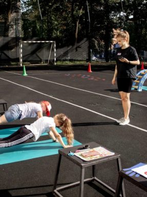 Бесшовное резиновое покрытие черного цвета на открытой спортивной площадке World Class во время тренировки детей с тренером