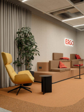 Ковровая плитка Desso в интерьере офиса Ergo с желтым креслом, многоуровневым подиумом и комбинированным зонированием пола.