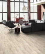 SPC-ламинат Tarkett Prime Click Birch Grey в интерьере гостиной лофта. Светло-серое напольное покрытие под дерево в зоне отдыха с диваном.