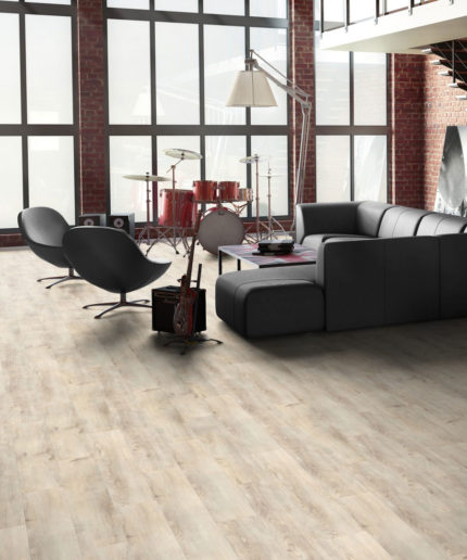 SPC-ламинат Tarkett Prime Click Birch Grey в интерьере гостиной лофта. Светло-серое напольное покрытие под дерево в зоне отдыха с диваном.