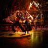 Танцевальный паркет Harlequin Liberty Ballroom на концертной сцене с огненным шоу. Профессиональное напольное покрытие Harlequin для бальных танцев во время экспрессивного парного выступления.