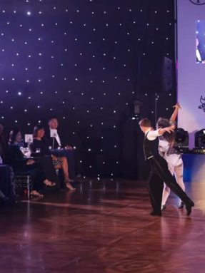Танцевальный паркет Harlequin Liberty Ballroom на благотворительном мероприятии Dance Against Dementia. Профессиональное напольное покрытие Harlequin для бальных танцев во время парного выступления на сцене.