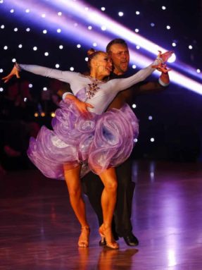 Пол Harlequin Liberty Ballroom на конкурсе бальных танцев во время экспрессивного выступления пары на фоне огней.